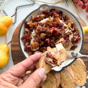 This gluten-free bacon and pear compote baked brie is the perfect gluten-free appetizer for the holidays. Whether you are entertaining friends or family everyone will love this hot dip. Saute pears, cranberries, raisins, cinnamon, walnuts and cayenne pepper, then add the bacon and top the brie and bake. Ooey gooey and oh so good!