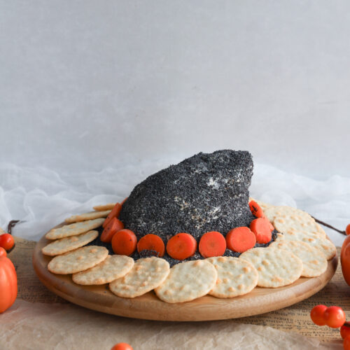 This homemade cheeseball is shaped into a witch hat and covered in poppyseeds or black sesame seeds. It is easy to make, ghoulishy delicious, kid friendly, fun to make and the perfect gluten-free appetizer for your Halloween party or scary movie night.