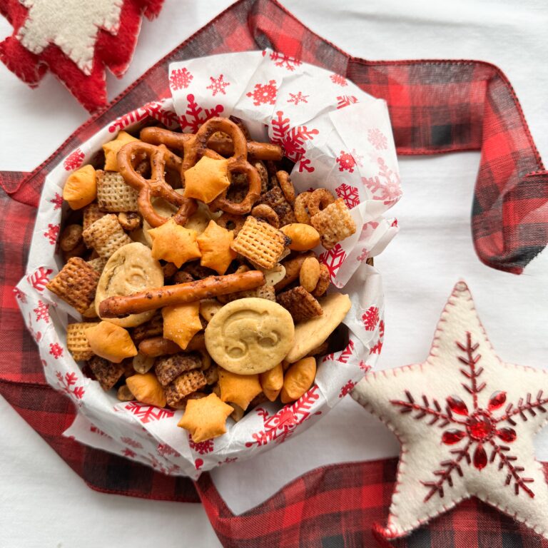 This gluten-free cheesy ranch Chex mix is easy to make and the perfect holiday snack as well as food gift for Christmas. It is salty, savoury and crunchy. A kid friendly gluten-free recipe. Made with rice and honey nut Chex, oat cereal, peanuts and pretzels. Add the butter mixture, stir and bake. Add the gluten-free cheese puffed star crackers and smiley face cheezy cracker bites. A fun and festive gluten-free snack.